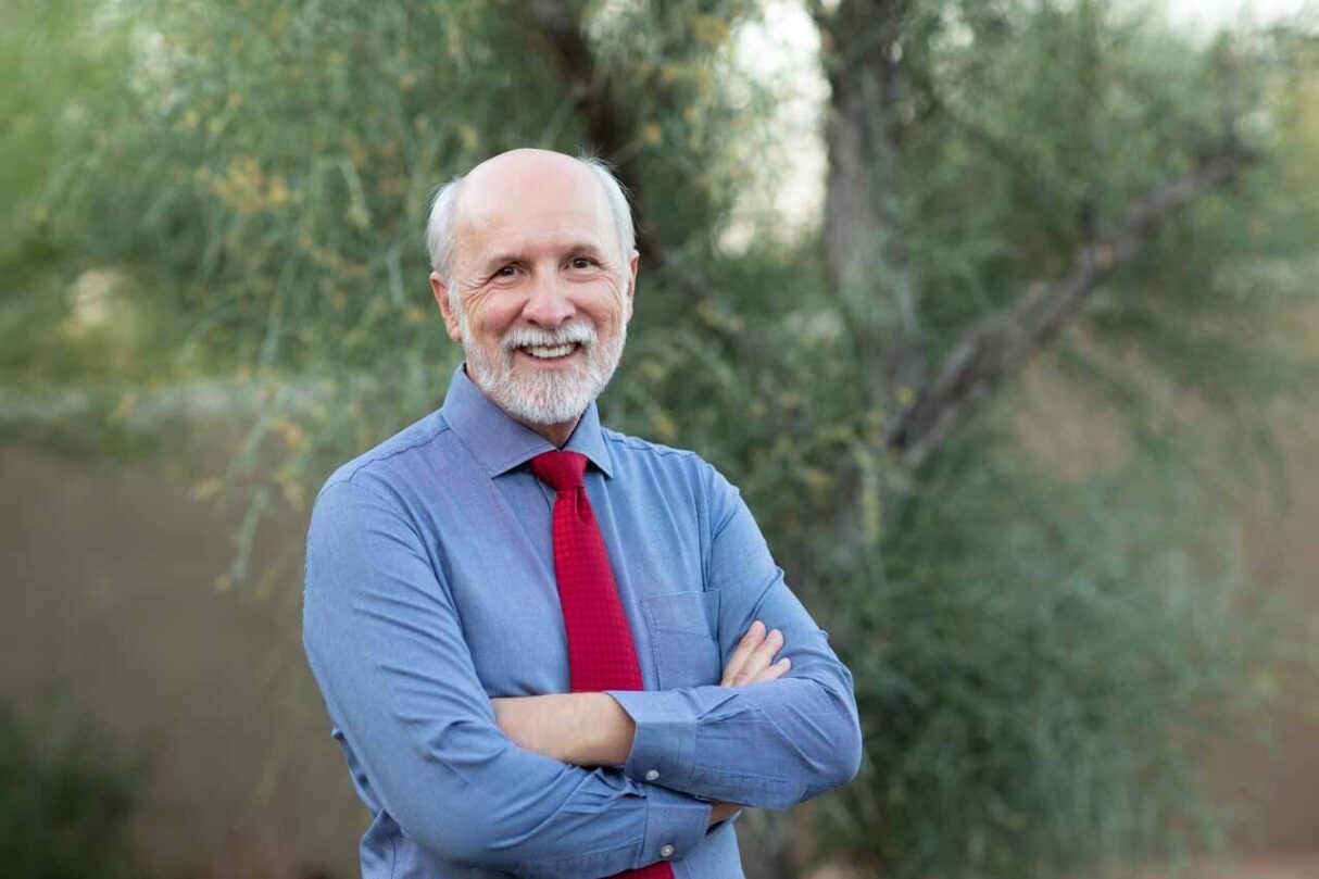 Man standing with hands folded, smiling